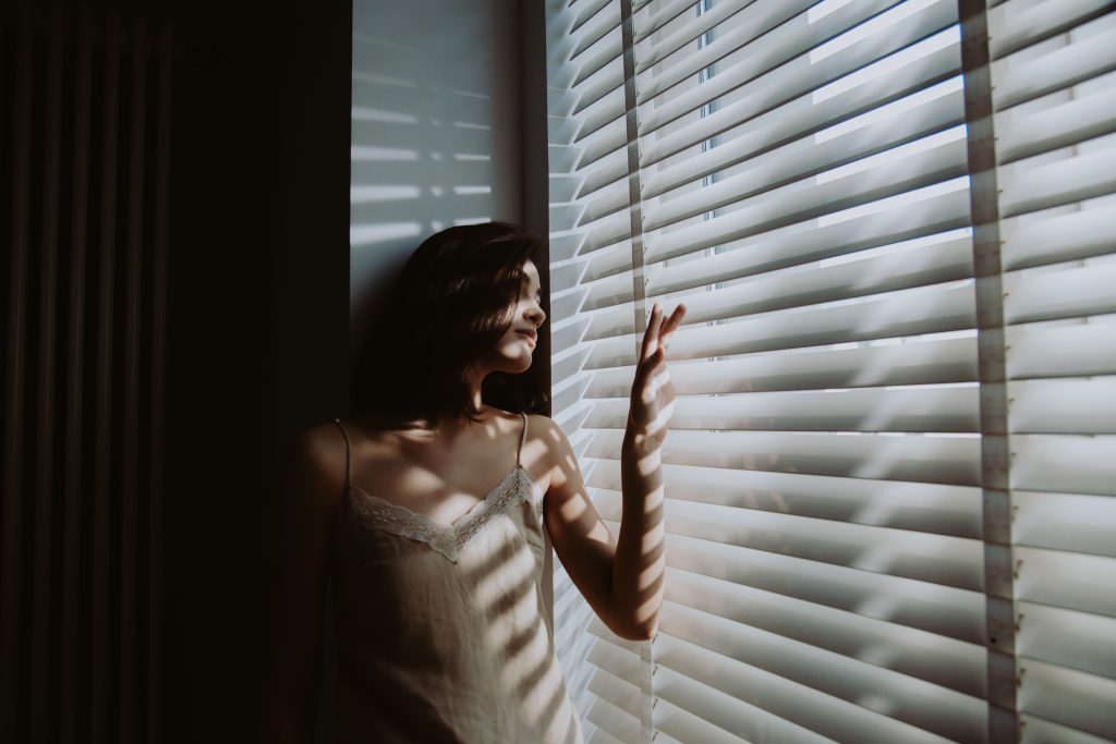 woman looking out window morning light